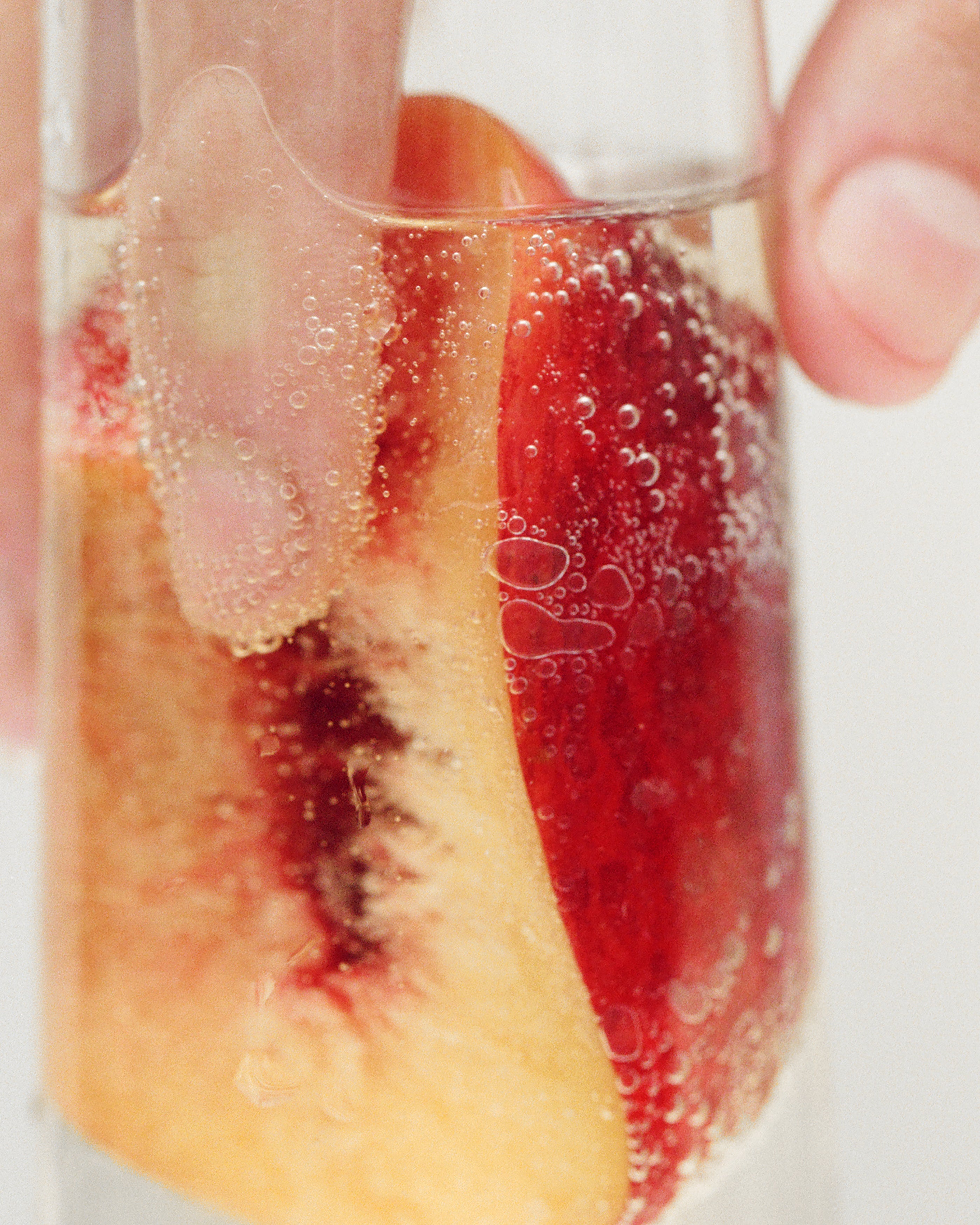 Peach slices in a glass of sparkling wine, seen through the bubbles