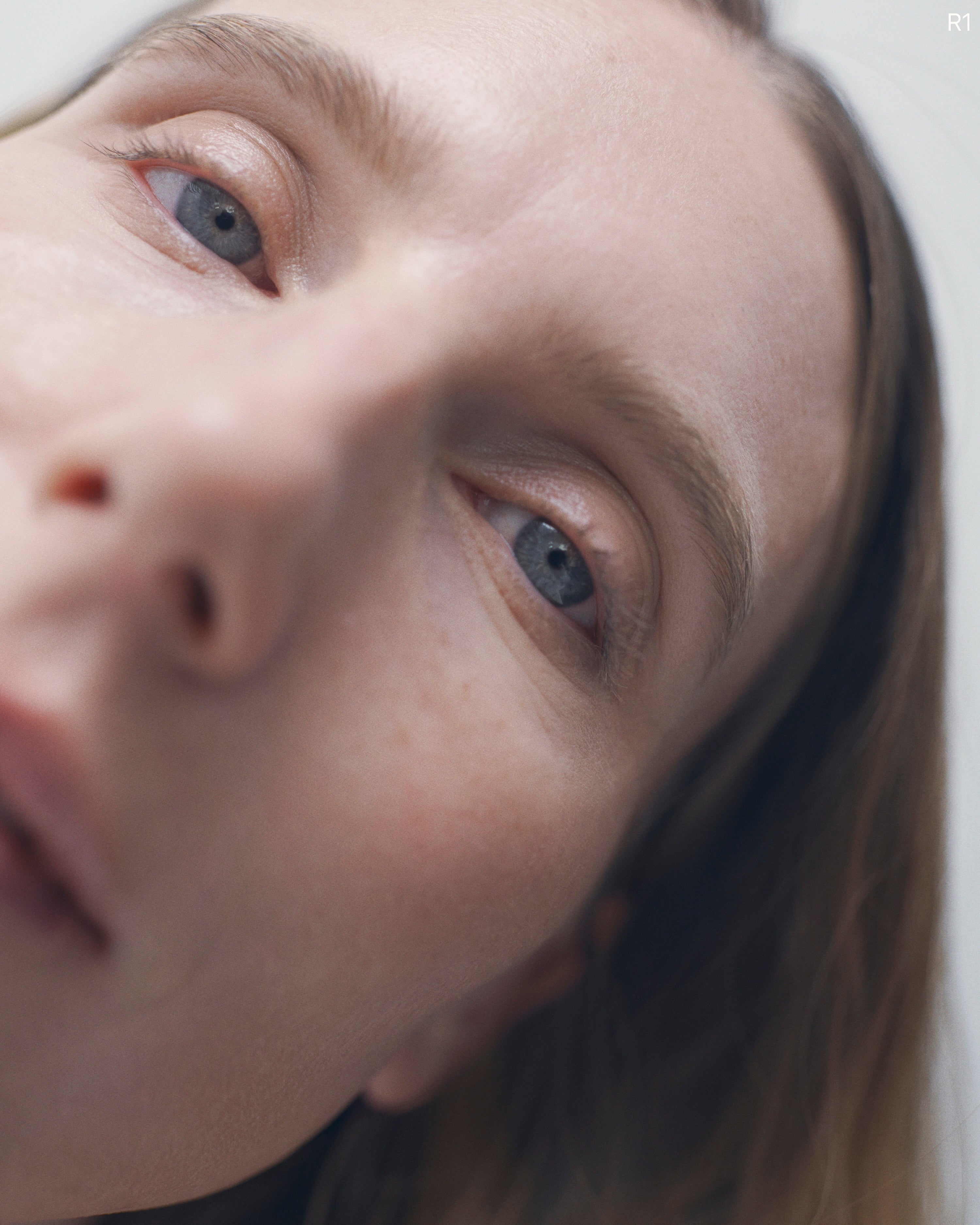Close portrait of a woman with pale blue eyes looking up past the camera